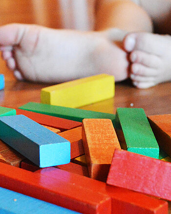 Ein Kind spielt mit Holzklötzen. Bild: Ein Kind spielt mit Holzklötzen.