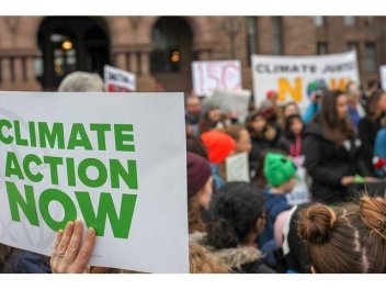 Demonstrierende halten ein Plakat hoch mit der Aufschrift "Climate Action now"